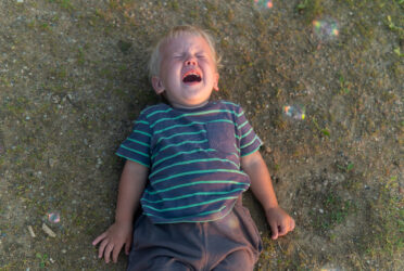 Un garçon part terre frustré, en pleine crise de pleurs