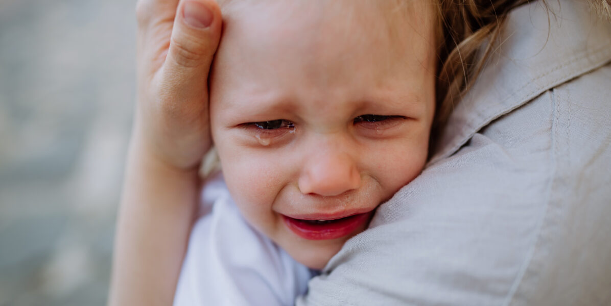 Enfant en pleine crise de terrible two dans les bras de sa maman