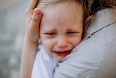 Enfant en pleine crise de terrible two dans les bras de sa maman
