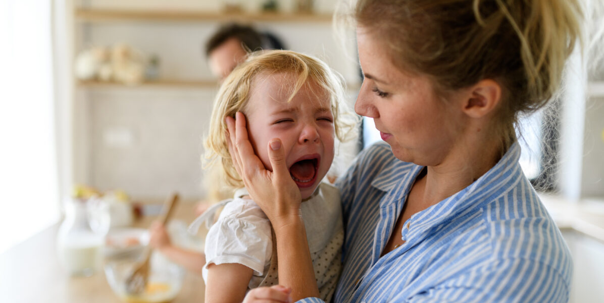 Petite fille qui pleure dans les bras de sa maman